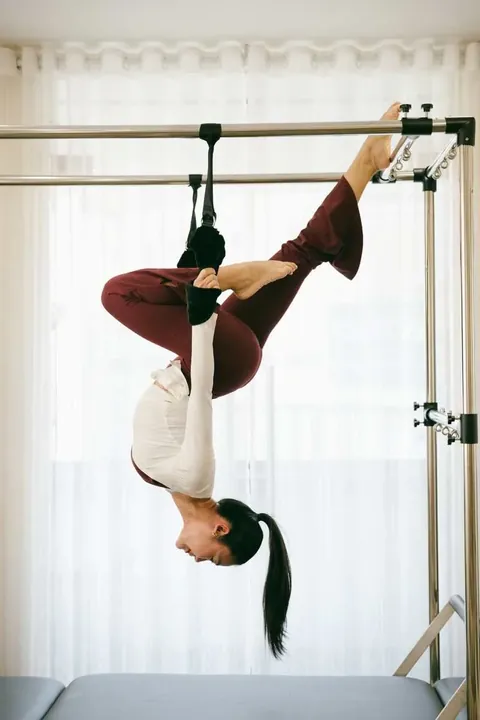 Ori Pilates client practicing a supported inversion on the Cadillac
